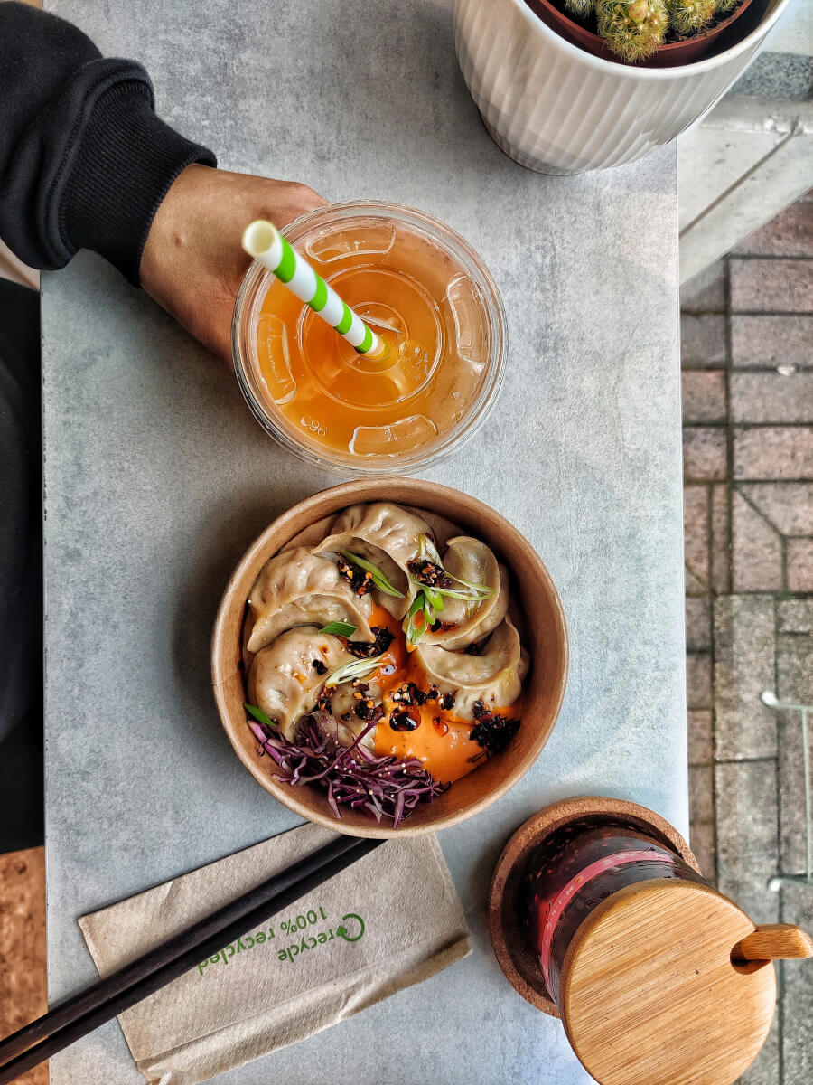 Top view of Marse momo bowl with a bottle of spice and a glass of drink on the side